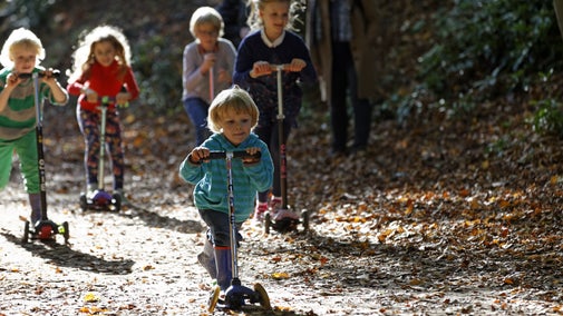 Children playing on scooters in the gardens at Cliveden, Buckinghamshire. Cliveden is nestled high above the River Thames with panoramic views over the Berkshire countryside.